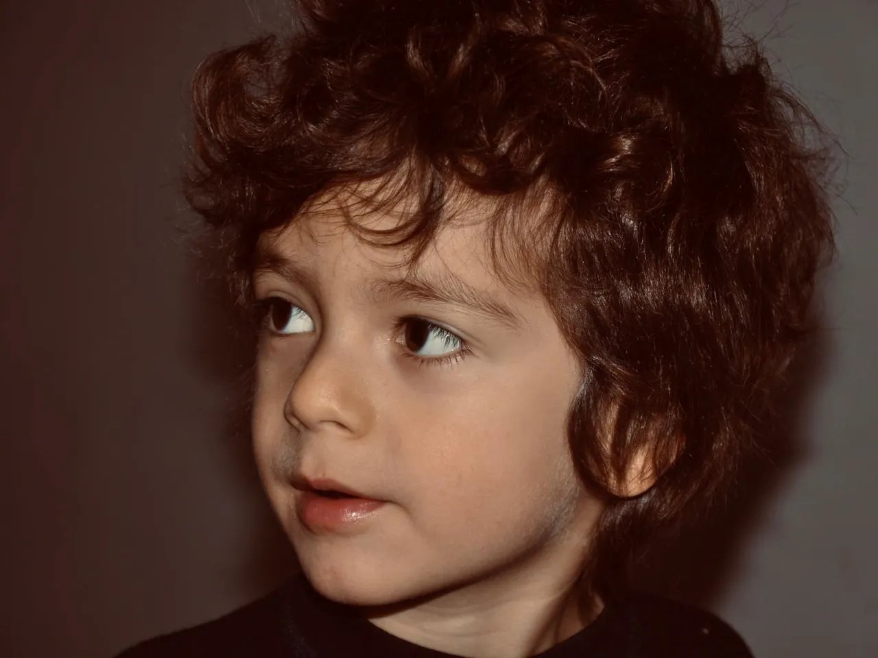 Retrato de un niño de pelo rizado mirando hacia un lado