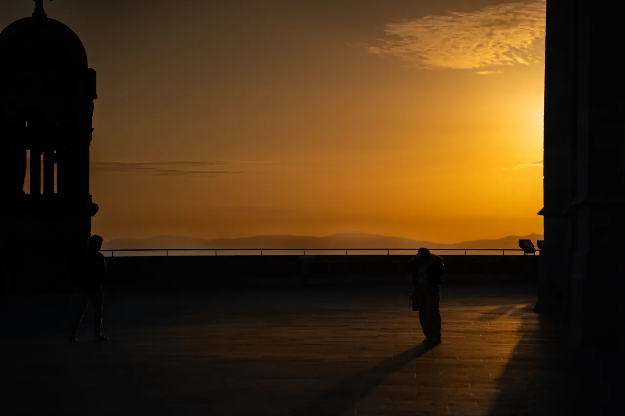 Silueta de una persona en una terraza durante una puesta de sol dorada