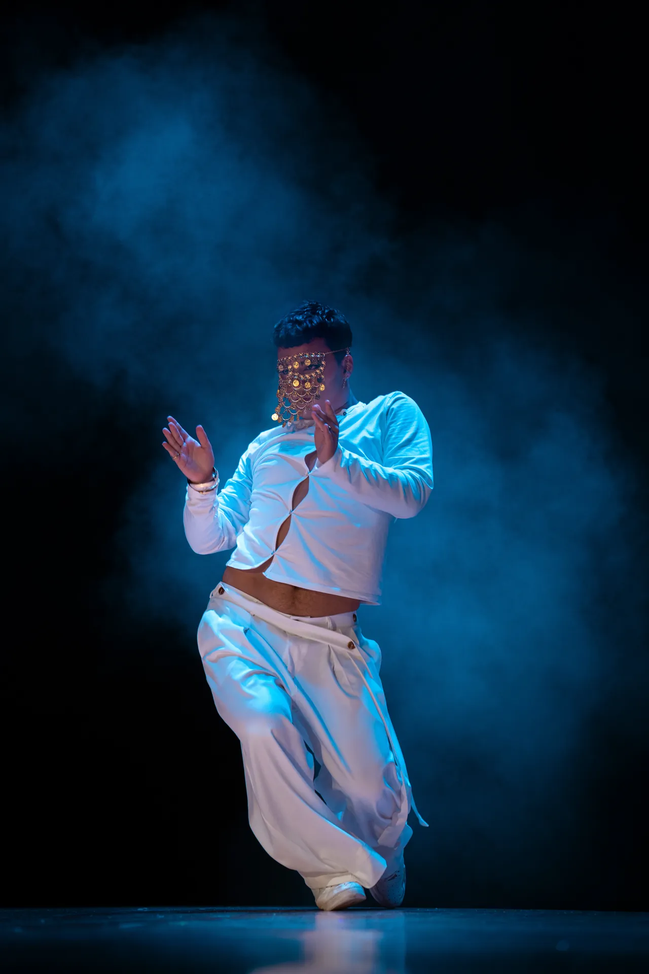 Bailarín vestido de blanco entre humo azul