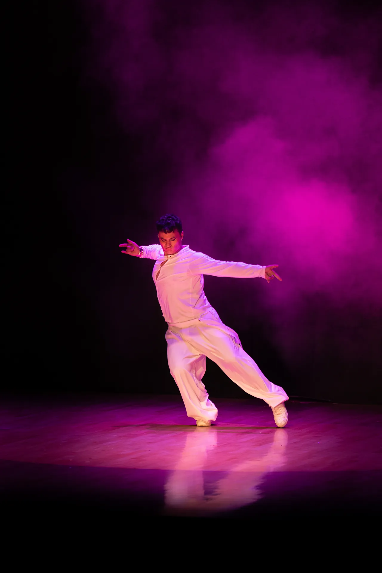 Bailarín de blanco en pleno salto bajo humo magenta