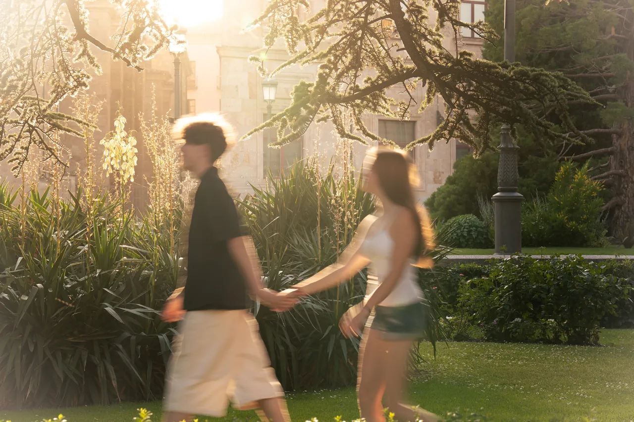 Pareja caminando de la mano por un jardín soleado