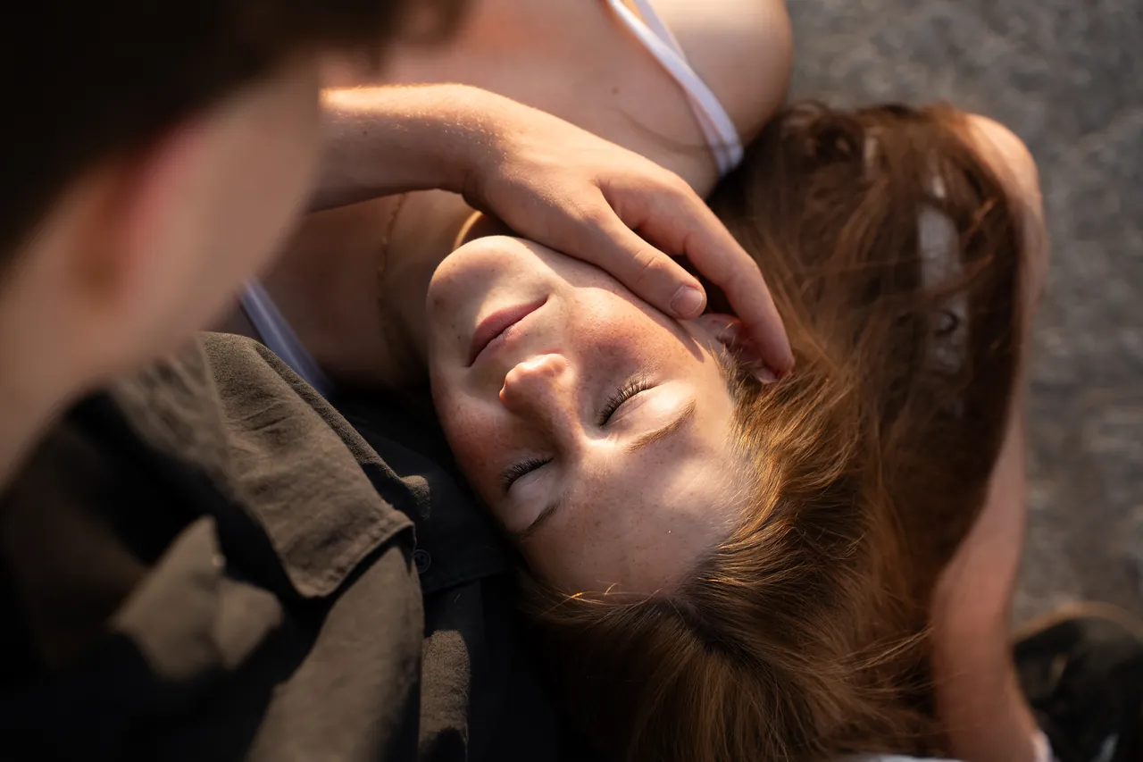 Chica con los ojos cerrados y la mano de él sobre su frente
