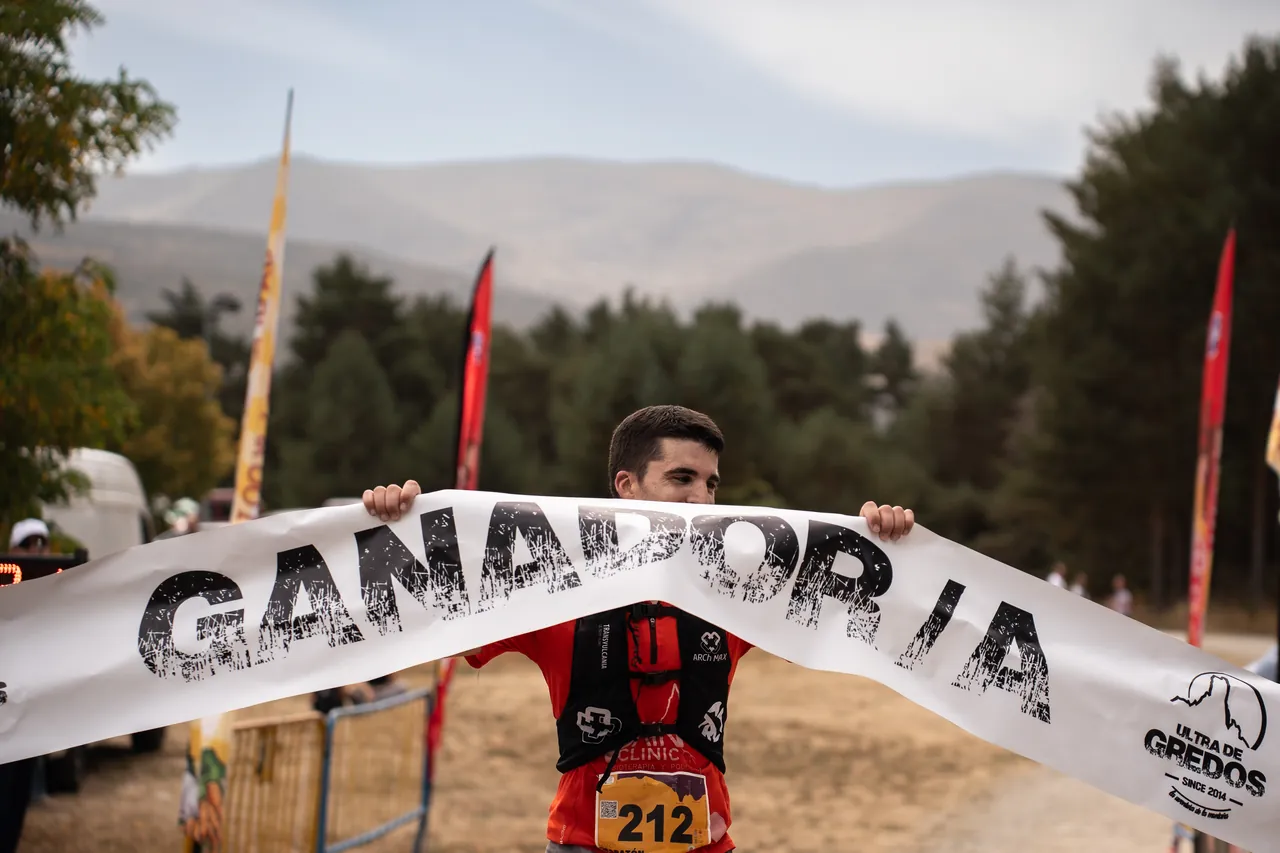 Ganador sosteniendo la pancarta de «Ganador/a» en la meta